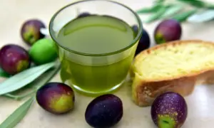 Olio extra vergine d'oliva e olive fresche, eccellenza dei prodotti DOP Puglia, accompagnati da una fetta di pane.