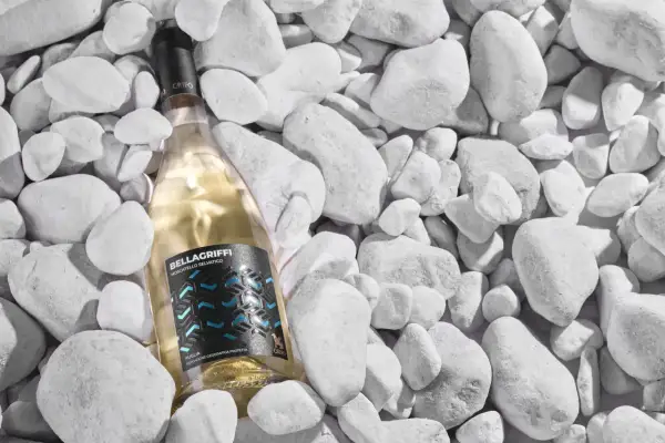Un vino pugliese bianco, Bellagriffi Moscatiello Selvatico, riposa tra ciottoli bianchi.