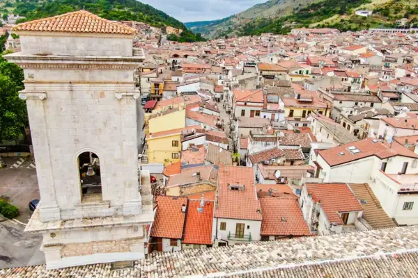 Vista dall'alto di San Marco in Lamis: un campanile in pietra domina un dedalo di tetti rossi e case arroccate tra le colline. Cosa vedere in questo borgo?